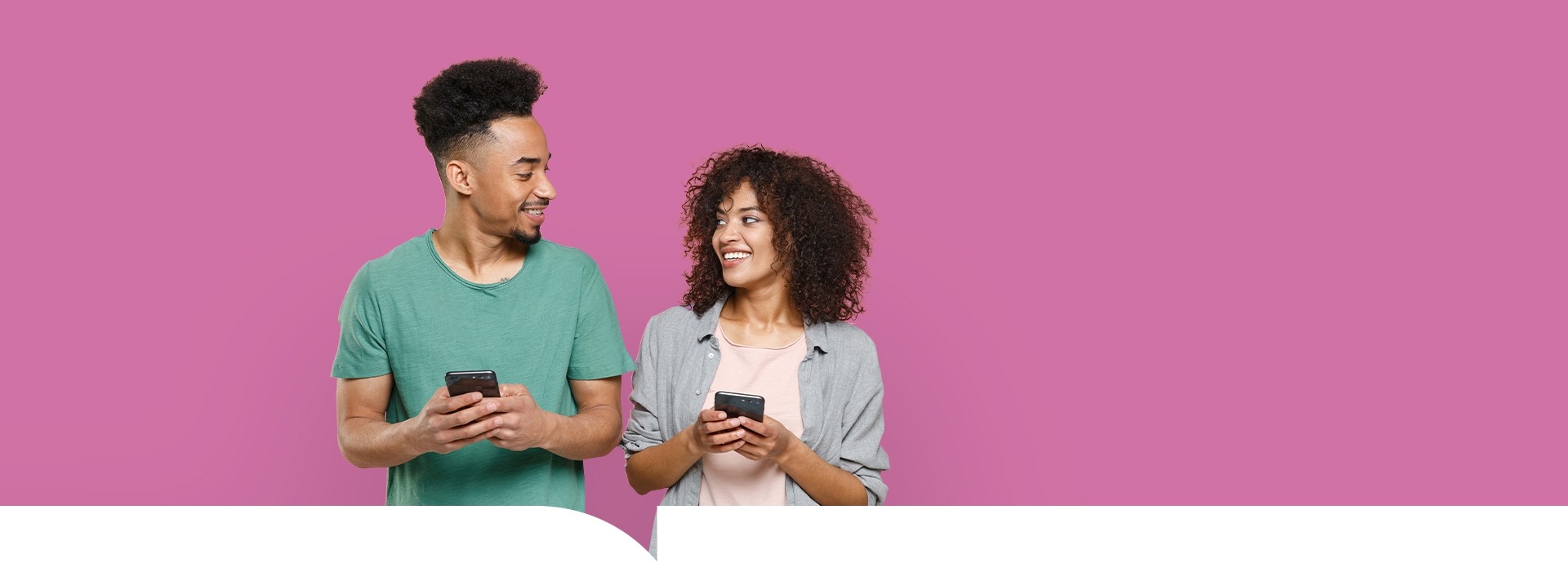 Een jong stel kijkt elkaar aan en houdt de telefoon vast op een roze achtergrond