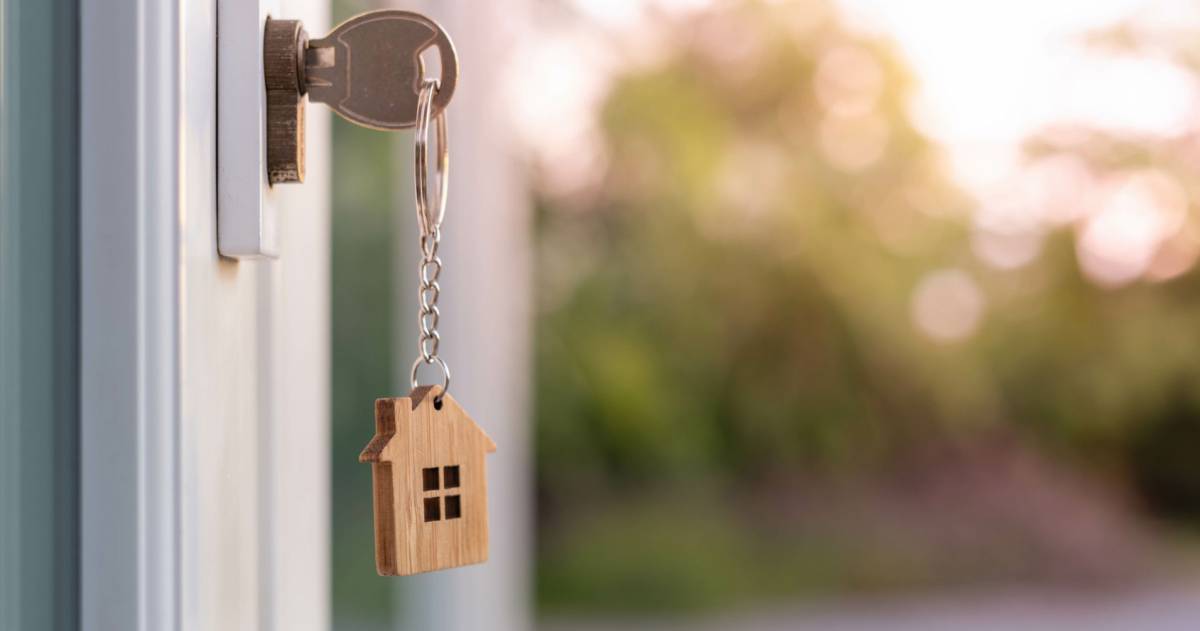 Een huissleutel met daaraan een sleutelhanger in de vorm van een huis. 